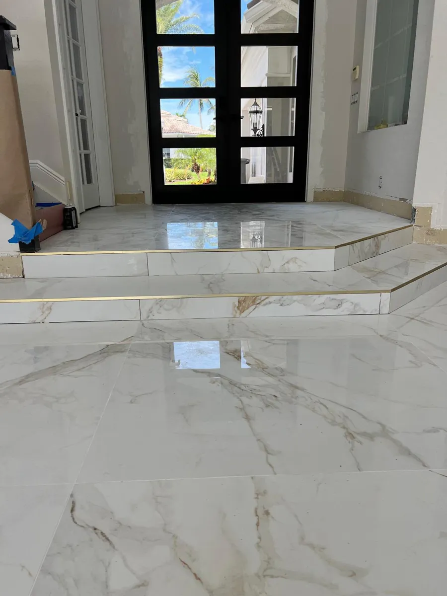 Polished white marble-look porcelain tile in an entryway with a raised step